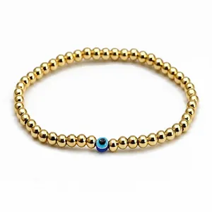 Detailed view of golden beads bracelet with a blue Evil Eye charm on white background