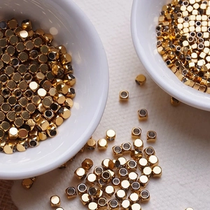 Vue macro de perles cubes dorées polies pour la création de bijoux DIY et colliers