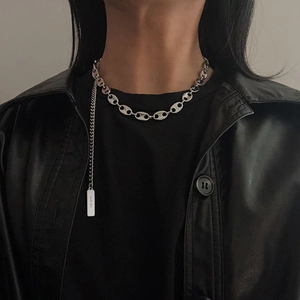 Close-up of stainless steel coffee bean chain necklace with engraved tag on a model