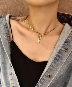Detail of a gold coffee bean chain necklace featuring a Roman numeral V crystal pendant