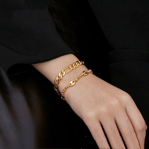 Polished gold stainless steel coffee bean link and Figaro chain bracelets worn on wrist