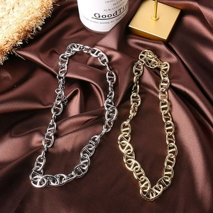 Macro view of gold and silver stainless steel pig nose clasp chains on brown silk cloth