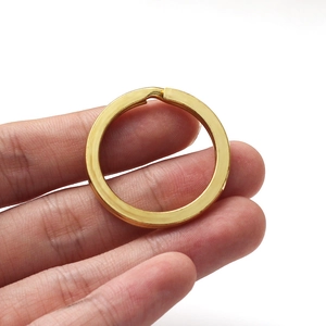 Macro shot of gold flat split key ring held by hand showing size and polished finish