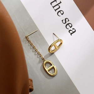 Detailed view of asymmetric gold pig nose buckle earrings with mirror finish metal texture