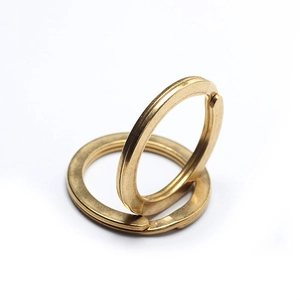 Close-up of two polished brass split key rings with flat metal wire design on white background