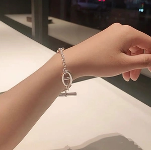 Detail of silver anchor chain bracelet featuring a toggle clasp on a model wrist
