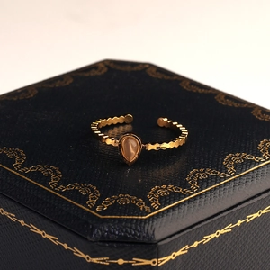 Dettaglio di un anello dorato a goccia d'acqua con bordi ondulati su portagioie elegante