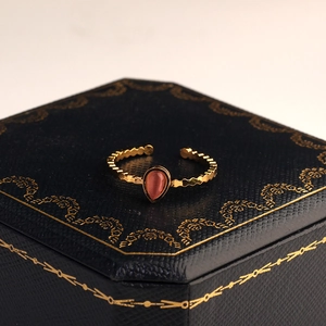 Macro di un anello a goccia dorato vintage con pietra rosa su scatola di velluto