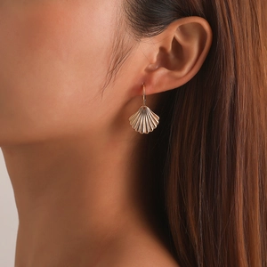 Elegantes pendientes de concha dorados para mujer con textura acanalada en primer plano