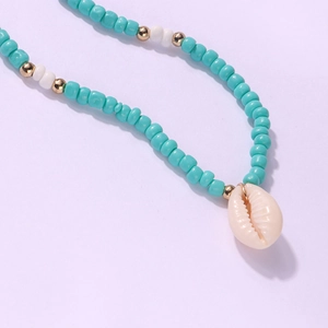 Dettaglio macro di perline turchesi e ciondolo a conchiglia su una collana con oro