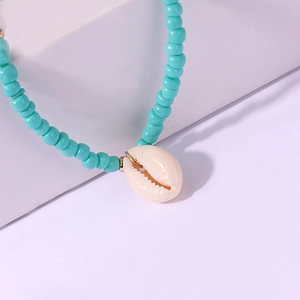 Dettaglio della collana di perline turchesi con ciondolo a conchiglia naturale su base