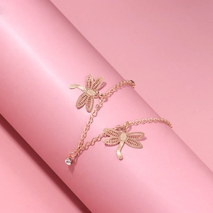 Rose gold hollow dragonfly anklet with sparkling zircon charm on a soft pink background