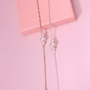 Elegante Gold- und Silberarmbänder mit minimalistischen Perlen auf einer rosa Box