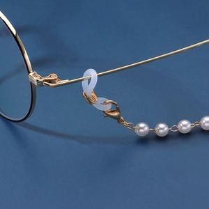 Elegant gold chain eyeglass holder with white pearls and lobster clasp on blue background