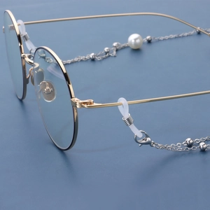 Lunettes rondes dorées avec chaîne élégante à pampilles en perles sur fond bleu foncé
