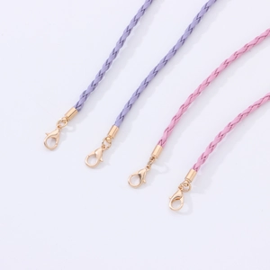 Detail of purple and pink braided leather cords with golden lobster clasps for eyewear