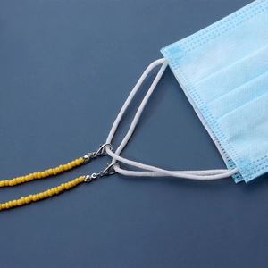 Macro detail of yellow beaded lanyard with lobster clasps attached to a blue medical mask