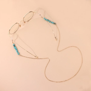 Chaîne de lunettes dorée bohème avec perles en turquoise sur fond rose poudré