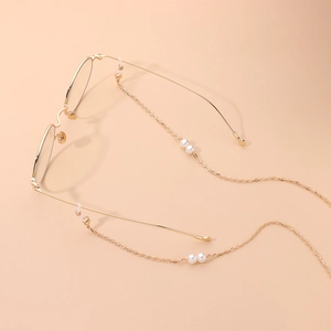 Chaîne à lunettes dorée élégante avec perles délicates sur fond abricot clair soigné