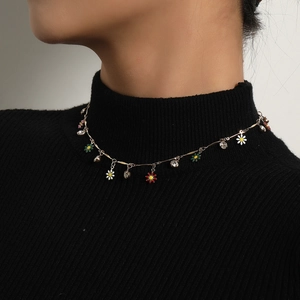 Elegantes Goldhalsband mit bunten Emaille-Gänseblümchen und Kristallanhängern auf Schwarz