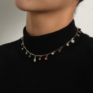 Luxuriöse goldene Emaille-Blumenkette mit Strasssteinen auf einem schwarzen Pullover
