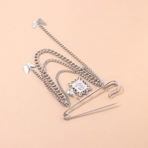 Silver layered butterfly and rose brooch with rhinestones and chain on beige background