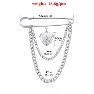 Vintage silver heart brooch with rose relief and draped double chains on white background