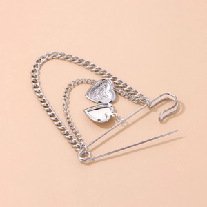 Silver locket brooch with relief flower patterns and double chains on cream background