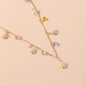 Detailansicht der Goldkette mit weißen Gänseblümchen und bunten herzförmigen Kristallen