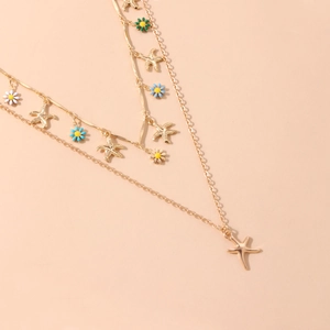 Macro detail of golden starfish charms and colorful enamel daisy flowers on layered necklace
