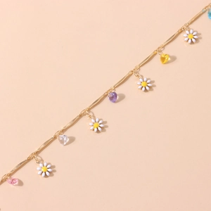 Detail der Goldkette mit weißen Gänseblümchen und bunten herzförmigen Kristallanhängern