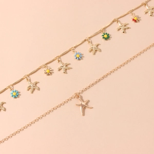 Macro view of double-layer gold anklet with starfish pendants and colorful enamel flowers