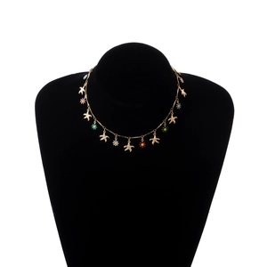 Golden Hawaiian necklace with colorful enamel daisies and starfish charms on a black display