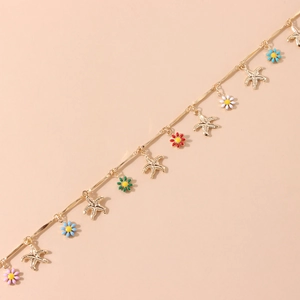Detailed close-up of golden necklace featuring colorful enamel daisies and starfish charms