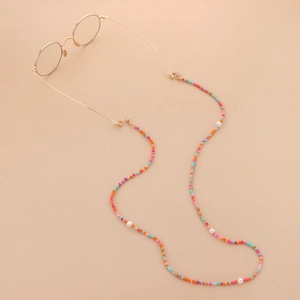 Dettaglio di perline colorate macaron e perle bianche su accessorio catena occhiali
