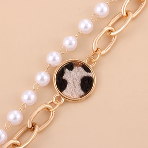 Detail von Goldkette und Perlenarmband mit rundem Anhänger im Leopardenmuster-Look