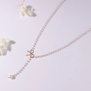 Detailansicht der Perlenkette mit goldenem Schleifenanhänger und elegantem Y-Design