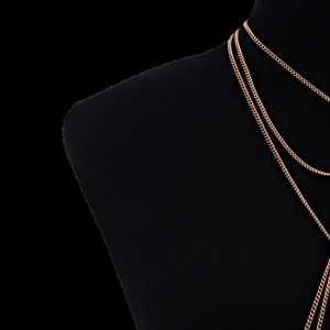 Detail of rose gold metal body chain with layered drapes on black velvet mannequin