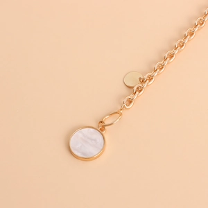 Macro shot of gold O-chain necklace featuring a white shell inlay circular pendant