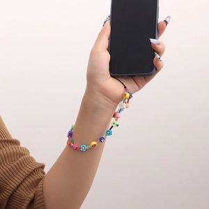 Dragonne de téléphone perlée colorée avec charms fruits et fleurs portée au poignet