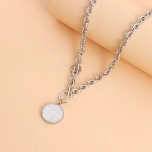 Detail of silver link necklace featuring an OT buckle and white marble circle pendant