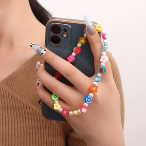 Bijou de téléphone perlé coloré avec fruits et cœurs sur un smartphone blanc