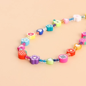 Gros plan de perles en argile colorées faites main avec fraises et motifs d'orange