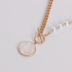 Detailed close-up of OT clasp and marble faux shell pendant on asymmetrical chain
