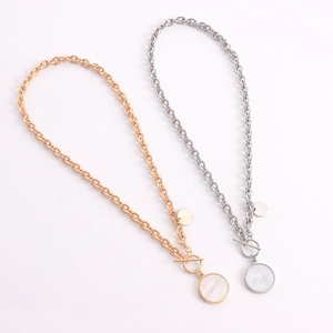 Detail of gold and silver chunky punk chains with mother-of-pearl pendants and OT clasp