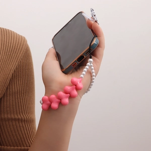 Pink heart and pearl beaded phone charm strap held by hand for a sweet fashion look