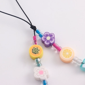 Vue détaillée de perles colorées en pâte polymère en forme de fruits sur un cordon de téléphone