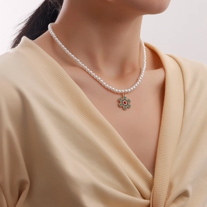 Elegant pearl necklace featuring a gold snowflake pendant with festive red and green accents
