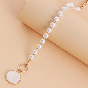 Detail of white pearl necklace with gold OT clasp and round shell-style pendant