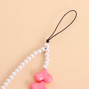 Detail of pink acrylic hearts and white faux pearls on a phone charm strap